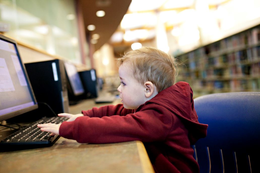 Toddler working at computer in the library